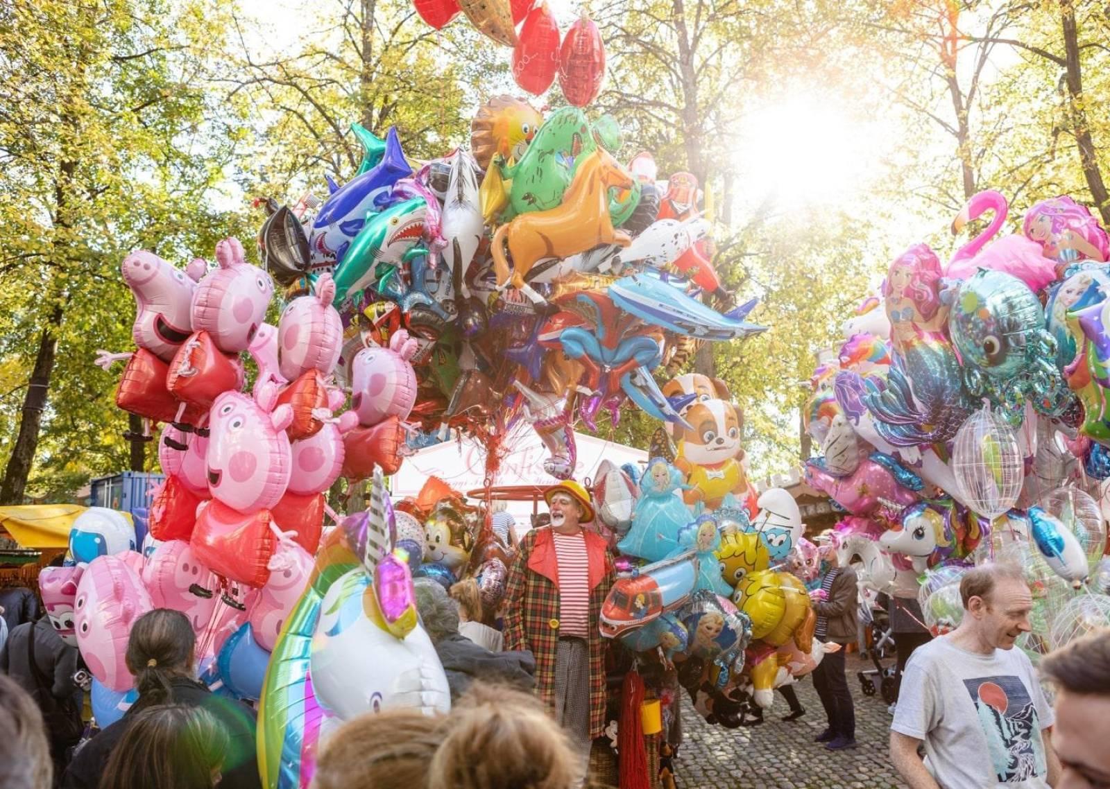 Un uomo allegro in Petersplatz con tanti palloncini di ogni colore e forma.