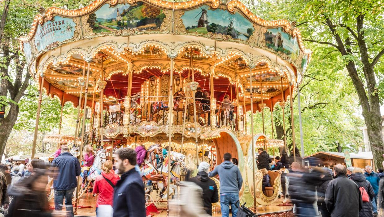 Des enfants tout sourire faisant du manège sur le traditionnel « Frankfurter-Pferdekarussell », magnifiquement décoré et illuminé, sous les grands tilleuls de la Petersplatz à Bâle.