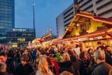 Evening ambiance with numerous Autumn Fair visitors in front of the brightly lit food stands on Basel's Messeplatz.